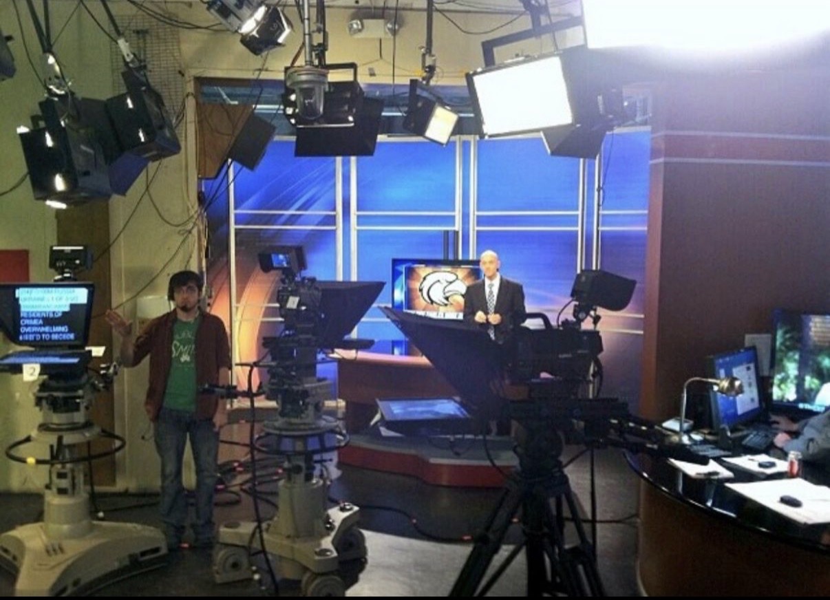 A television news studio with cameras, lights, and a presenter on set